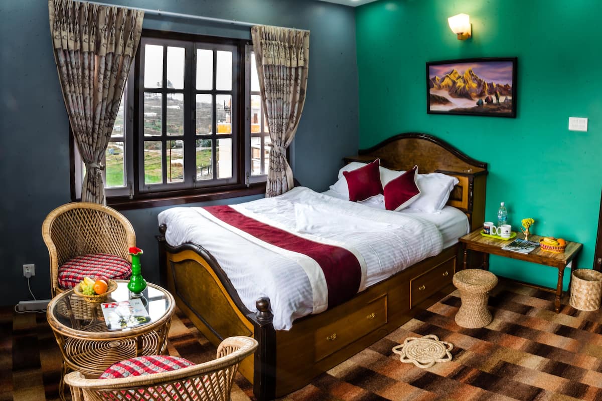 Un dormitorio con cama, muebles de mimbre, una ventana, un cuadro y una puerta roja.