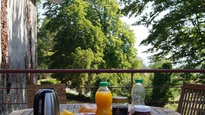 Une table en bois, dressée pour le petit-déjeuner, avec une bouilloire, du jus de fruits et du café.