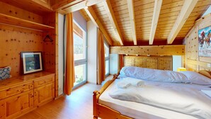 Une chambre dans une cabane en bois, avec un lit, une commode et un tableau encadré au mur.