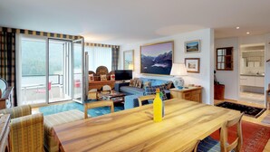A spacious living area with a wooden dining table, a sofa set, and a large window offering a view of the outdoors. - Terraced apartmentbuilding between St. (St. Moritz)