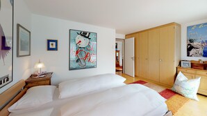 A hotel room with a bed, a wardrobe, a desk with a lamp, and a wall with a framed picture. - Terraced apartmentbuilding between St. (St. Moritz)