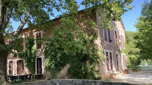 A historic building with a stone facade, large windows with shutters, and a surrounding garden. - Secular Manor: Pool & 2.5ha Estate – Perfect for Families & Friends (Roussillon)