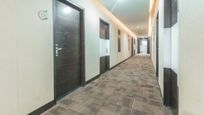 A long hallway with doors on both sides, a patterned carpet, and a light-colored wall. - Collection O Cikarang Near Pollux Mall Formerly Hotel Pesona Cikarang (Cikarang)