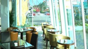 An indoor seating area with tables and chairs, large windows, and a view of the street outside. - Collection O Cikarang Near Pollux Mall Formerly Hotel Pesona Cikarang (Cikarang)