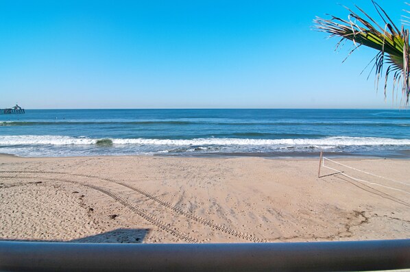 A beach with a volleyball net, clear skies, and calm waves.