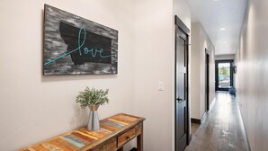 Un pasillo con una consola de madera, una planta en maceta y un letrero en la pared que dice 'love'.