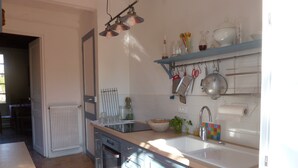 Cuina moderna amb forn integrat, rentapelats i una superfície de treball. Hi ha diversos utensilis de cuina i una finestra que aporta llum natural.