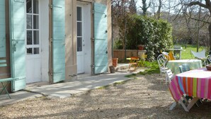 Un edifici rústic amb un camí de grava que condueix a un pati amb mobles d'exterior.