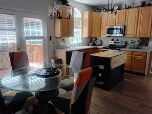 Una cocina moderna con armarios de madera, una mesa de comedor de vidrio y un microondas integrado.
