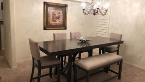 A dining room with a dark wooden table, six chairs, a bench, a chandelier, and a framed picture on the wall. - Very nice 4 bdrm 2 full bath ranch home w/ great room in quiet neighborhood. (Phoenix)