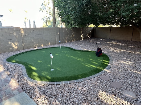 Um campo de mini golfe com putting green, uma sacola de bolas de golfe e uma sacola de tees.