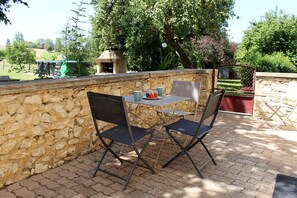 Eine Terrasse mit Steinmauern, einem Tisch und zwei Stühlen.
