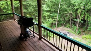 A wooden deck with a grill and propane tank, overlooking a forested area. - Private Brook Side Log Cabin  on Tenney Mountain (Plymouth)
