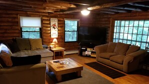 A cozy cabin interior with two sofas, a coffee table, a TV, and a fireplace. - Private Brook Side Log Cabin  on Tenney Mountain (Plymouth)