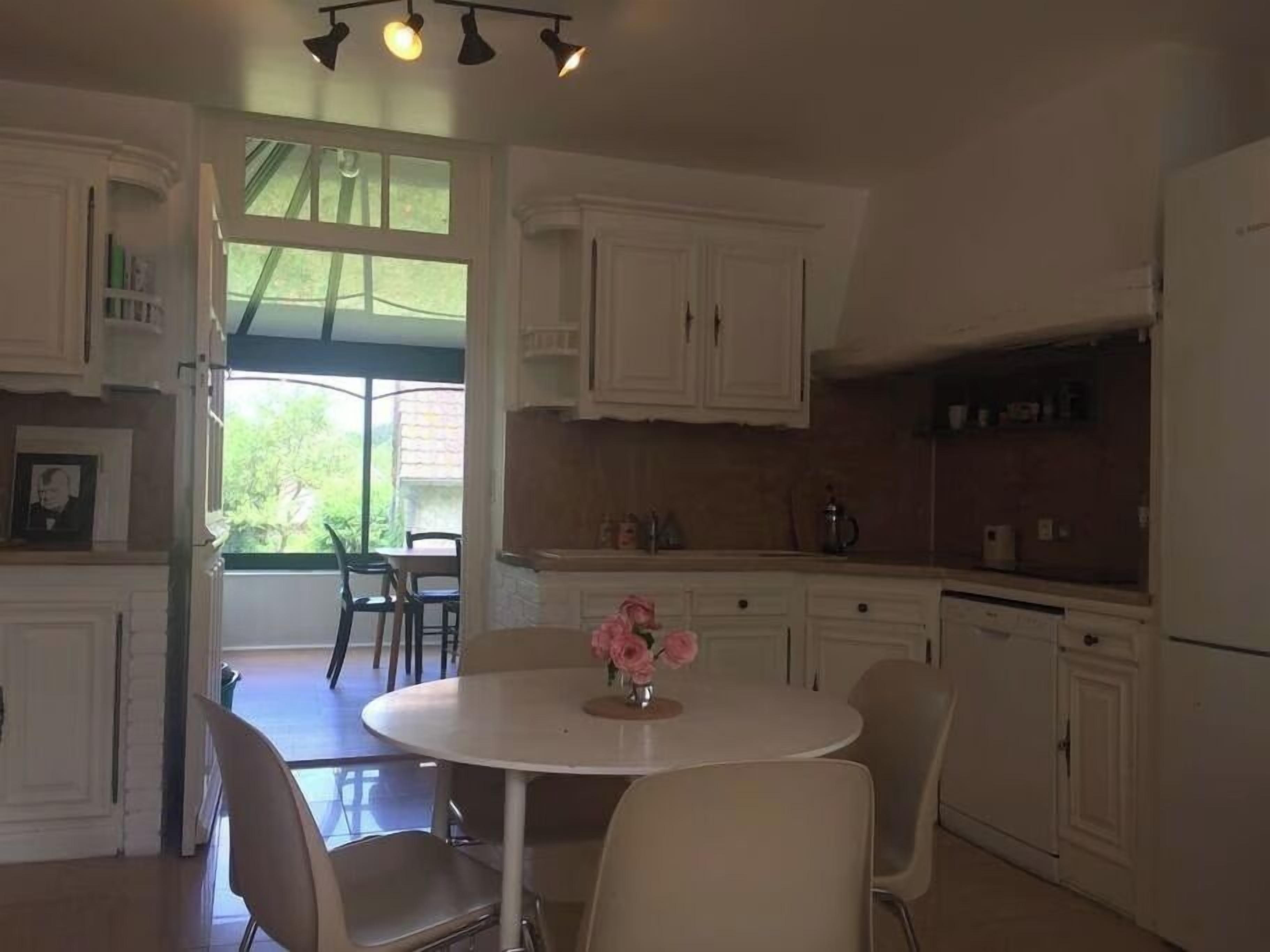 A kitchen with white cabinets, a dining table with chairs, and a refrigerator.