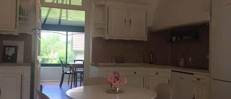 A kitchen with white cabinets, a dining table with chairs, and a refrigerator.