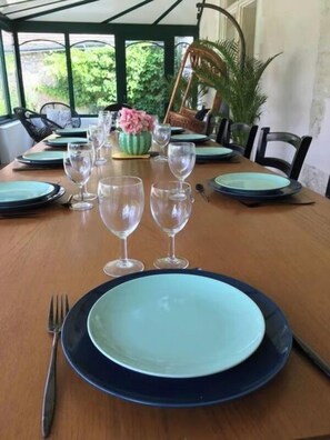A dining table set with plates, glasses, and cutlery, surrounded by chairs.