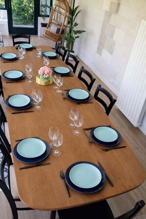 A dining table set with plates, glasses, and cutlery, surrounded by chairs.