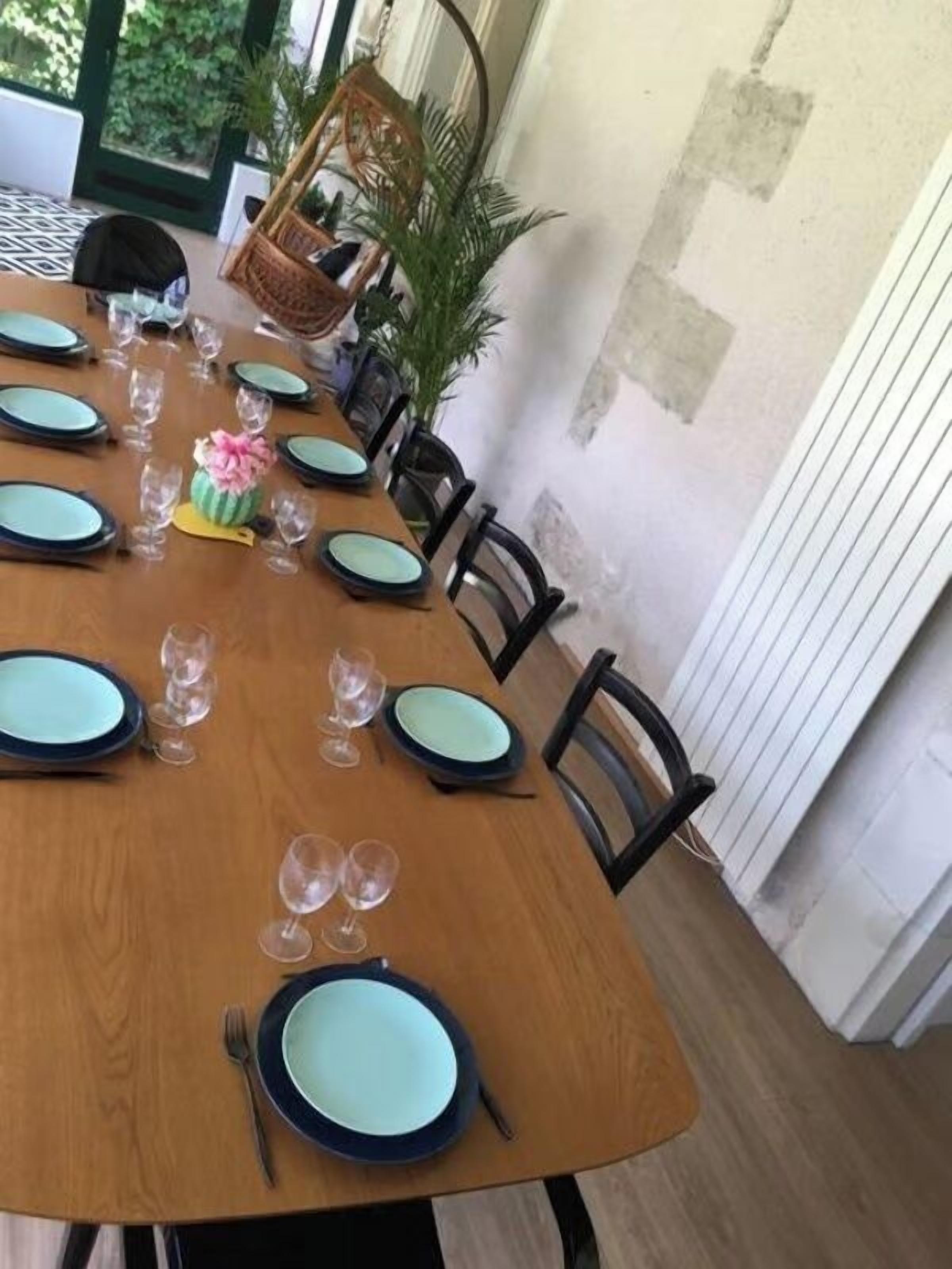 Een eettafel gedekt met borden, glazen en bestek, omringd door stoelen.