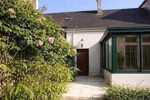 Een huis met een tuin, een houten deur en een raam met een groene omlijsting.