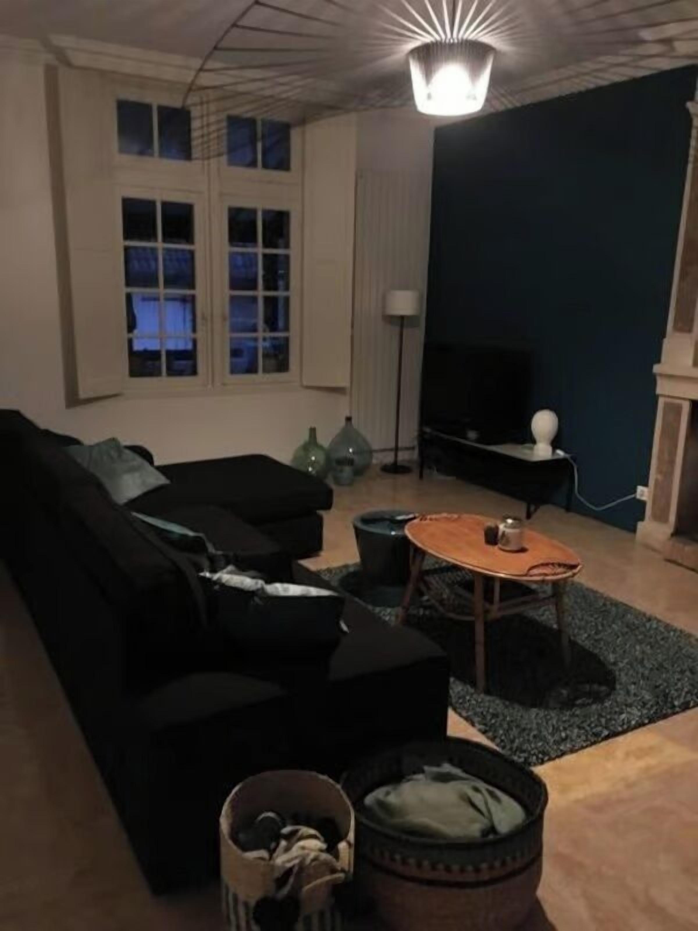Ett vardagsrum med en soffa, ett soffbord, en tv och en öppen spis.