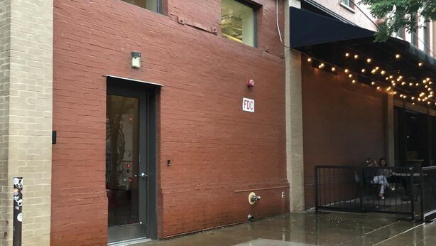 A red brick building with a glass door and windows, an outdoor seating area with string lights, and a sign reading "FDC". - "Market View" 2Br, 2ba, Best view of the Market Square, Great Location (Knoxville)