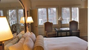 Una camera d'albergo con un letto grande, due poltrone, un tavolino e uno specchio.