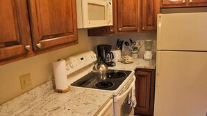 Una cucina con mobili in legno, un fornello, un forno a microonde e un frigorifero.