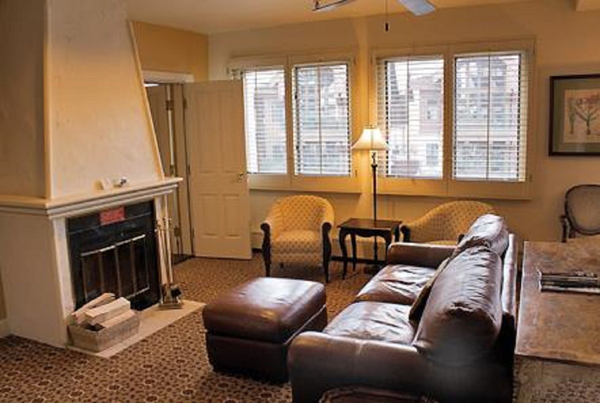 A living room with a fireplace, a sofa, armchairs, and a table.