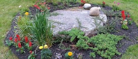 Stunning garden oasis with lush greenery and vibrant blooms surrounds a central stone feature.