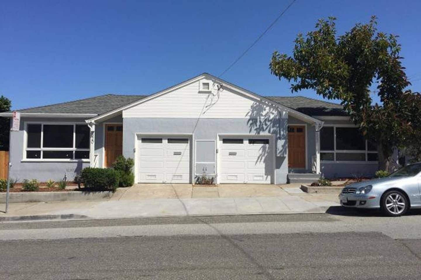 A two-story house with a garage, a driveway, and a parked car.
