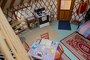 Une pièce chaleureuse avec une petite kitchenette, une table à manger avec des chaises, un tapis à motifs et une structure murale en bois.