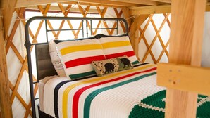 Ein Bett mit einer gestreiften Bettdecke und einem Häkelkissen.
