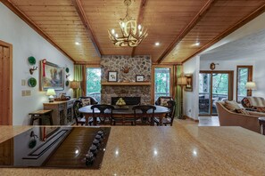 Un vaste espace de vie doté d’une cheminée en pierre, d’un plafond en bois et d’une table à manger avec des chaises.