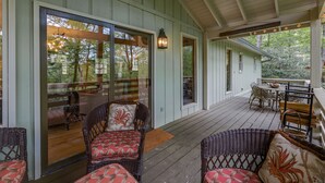 A covered porch with wicker furniture, a dining area, and a sliding glass door leading to an outdoor space.