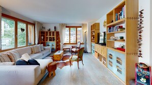 A spacious living room with a sofa, chairs, a coffee table, and a bookshelf. - Popular and centrally located residential building in St. (St. Moritz)