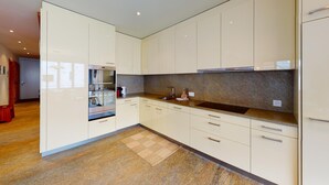 A modern kitchen with white cabinets, a granite countertop, and a built-in oven. - Popular and centrally located residential building in St. (St. Moritz)
