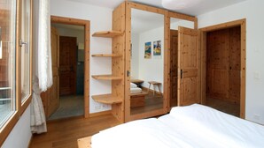 A bedroom with a bed, wooden wardrobe, and a mirror cabinet. - Popular and centrally located residential building in St. (St. Moritz)