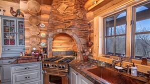 Una cocina rústica con un horno de piedra, armarios de madera y un ventanal grande.