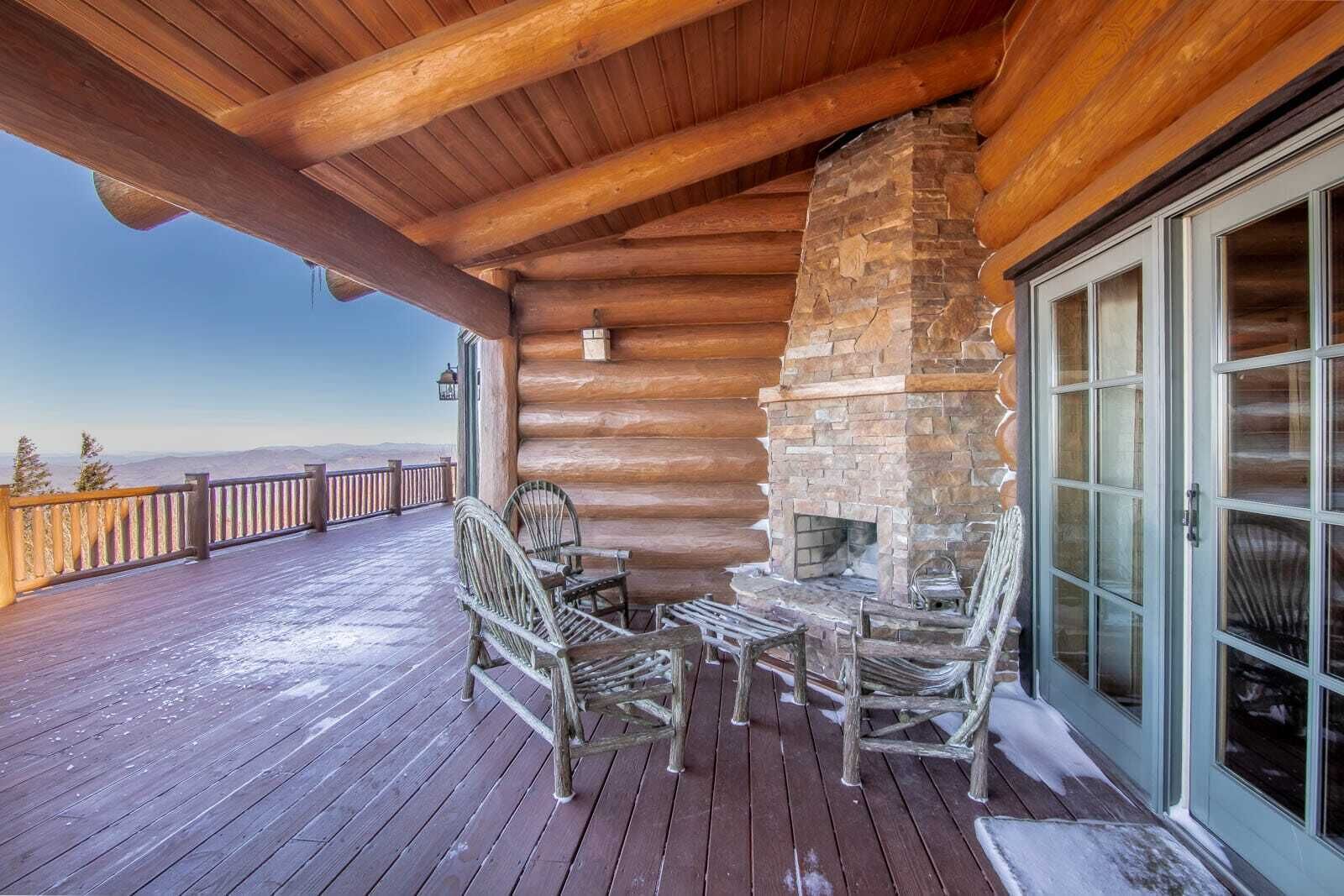 Eine Holzterrasse mit einem Steinkamin, Korbstühlen und einer Glastür.