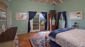 Un dormitorio con una cama, un aparador, un espejo y una puerta que da a un balcón.