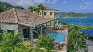 Una villa con piscina, mobiliario de exterior y vistas al mar.