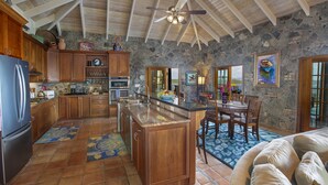 Una cocina amplia con armarios de madera, una isla grande y un fondo de pared de piedra.
