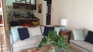 Ein Wohnzimmer mit einer Couch, einem Couchtisch und einem Essbereich im Hintergrund.