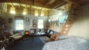 Una habitación acogedora con cama, sofá, escritorio y una escalera.
