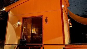 Un pequeño edificio naranja con puerta de vidrio y escalones que suben a él.