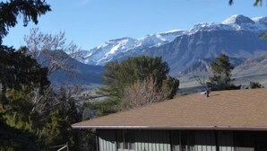 Un bâtiment doté d’un toit plat, entouré d’arbres et avec des montagnes en arrière-plan.
