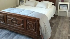 A bedroom with a wooden bed, white bedding, a patterned wallpaper, and two bedside tables with lamps. - Pretty Potters' House (Accolay)