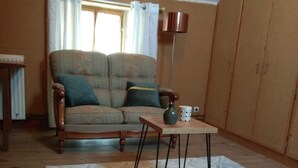 A living room with a sofa, a coffee table, a floor lamp, and a cabinet. - Pretty Potters' House (Accolay)