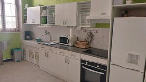 A kitchen with white cabinets, a microwave, a toaster, and a refrigerator. - Pretty Potters' House (Accolay)